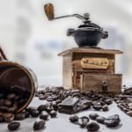 A burr coffee grinder, coffee beans, and a mug, illustrating the article on burr grinders.