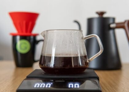 A pour-over stand with scale, coffee brewing equipment, and a glass carafe filled with brewed coffee.