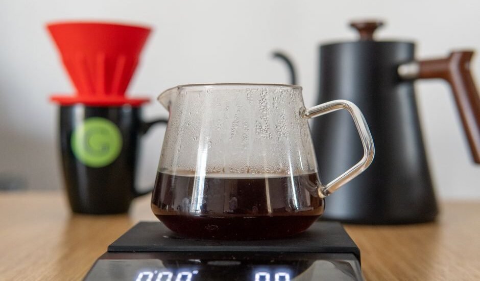A pour-over stand with scale, coffee brewing equipment, and a glass carafe filled with brewed coffee.