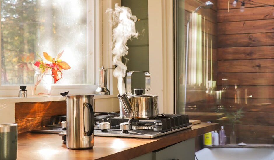 A stovetop kettle steaming on a gas stove next to a French press, illustrating the stovetop vs electric kettle debate.
