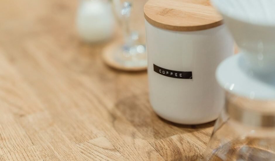 A vacuum coffee canister labeled 'coffee' on a wooden table, relevant to coffee storage.