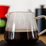 A glass thermal carafe filled with brewed coffee, showcasing its design and function.