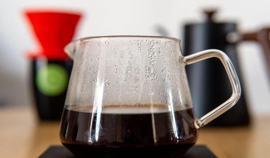 A glass thermal carafe filled with brewed coffee, showcasing its design and function.