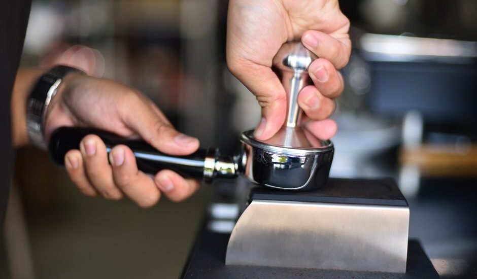A person tamping espresso grounds in a portafilter, illustrating the tamping process.