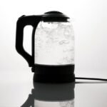 A corded electric kettle boiling water, illustrating the difference between corded and cordless kettles.
