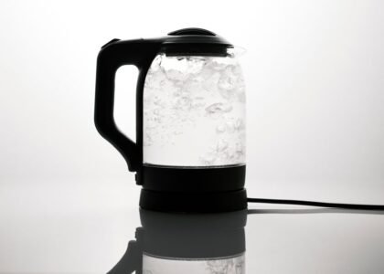 A corded electric kettle boiling water, illustrating the difference between corded and cordless kettles.