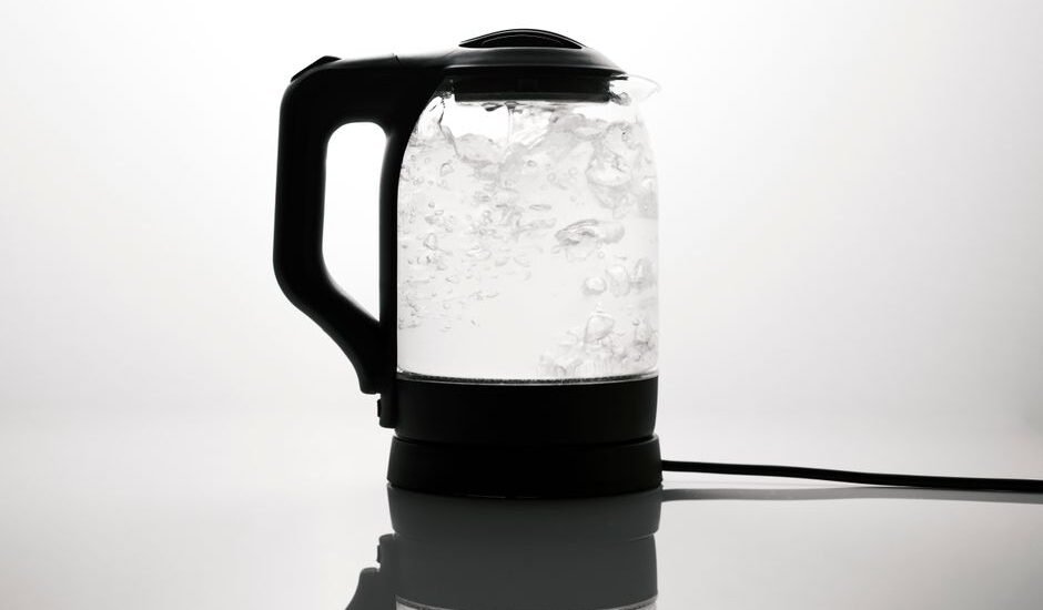 A corded electric kettle boiling water, illustrating the difference between corded and cordless kettles.