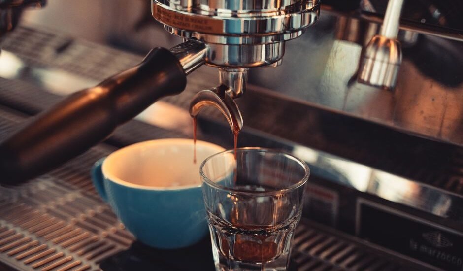 A close-up of espresso being extracted into a glass and cup, illustrating single vs double filter espresso.
