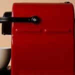 A red single-serve pod coffee maker next to a white cup, relevant to coffee maker reviews.