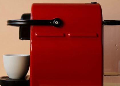 A red single-serve pod coffee maker next to a white cup, relevant to coffee maker reviews.
