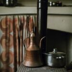 A copper kettle and a stainless steel pot on a stove, relevant to kettle comparison.