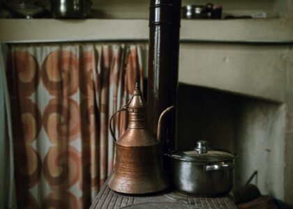 A copper kettle and a stainless steel pot on a stove, relevant to kettle comparison.