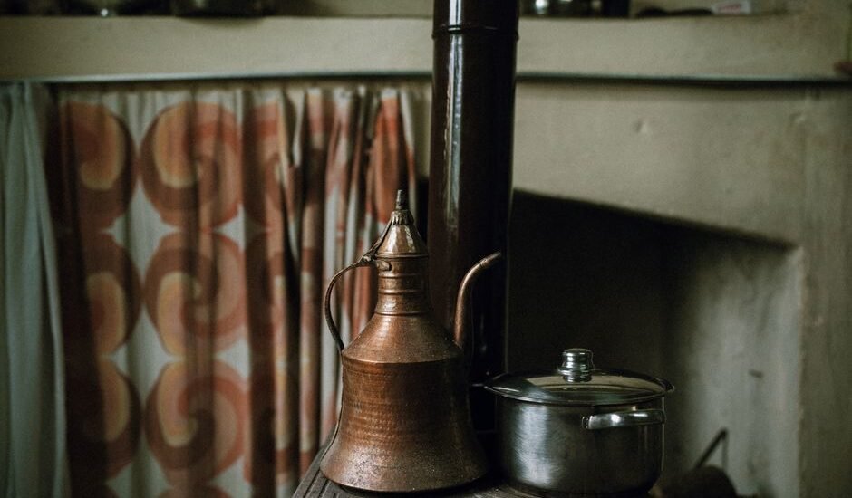 A copper kettle and a stainless steel pot on a stove, relevant to kettle comparison.