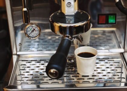 A close-up of an espresso machine showing a pressure gauge and a cup of brewed coffee, relating to ideal espresso pressure.